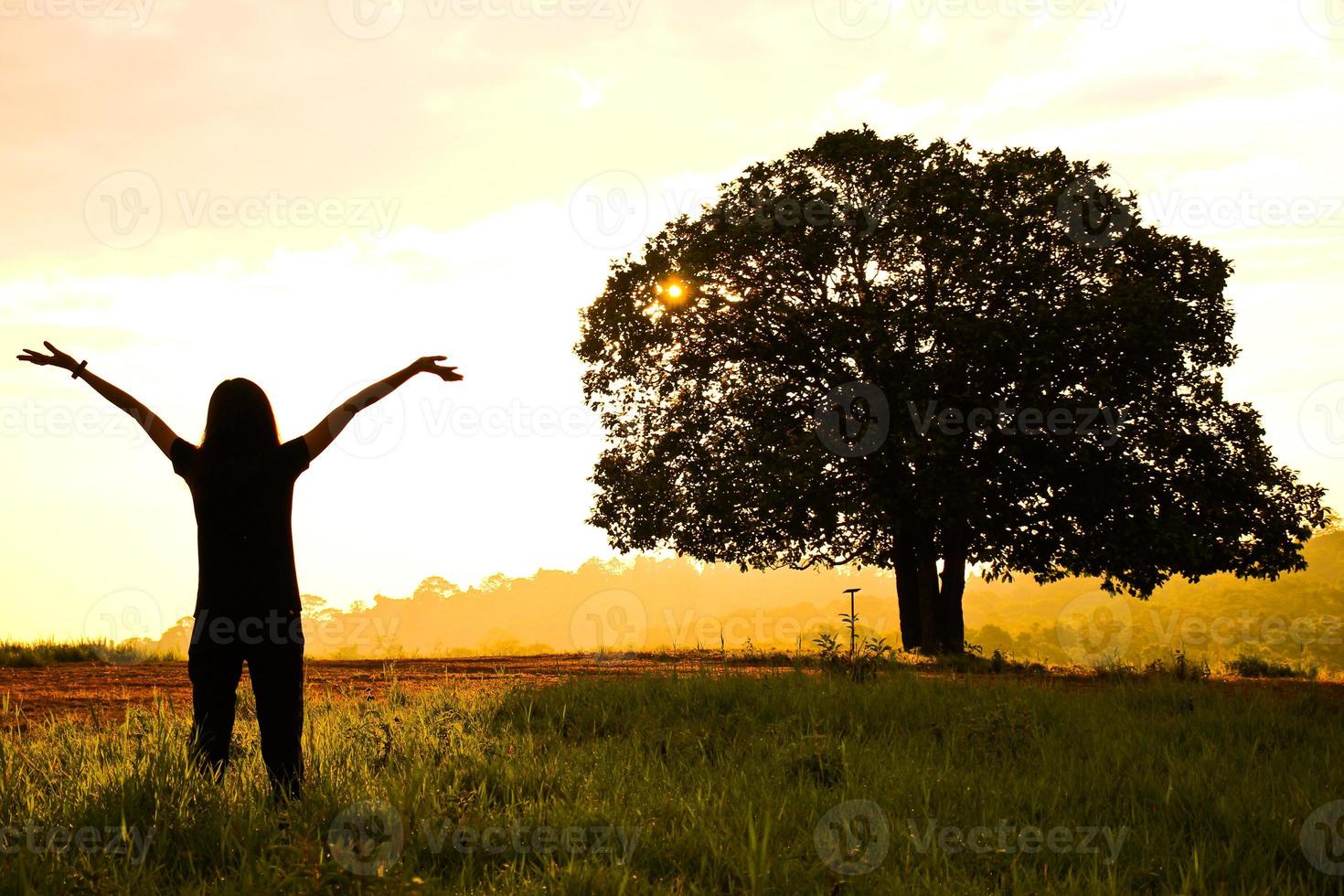 de vrouw stak haar hand in de wei met haar gezicht naar de zonsopgang foto