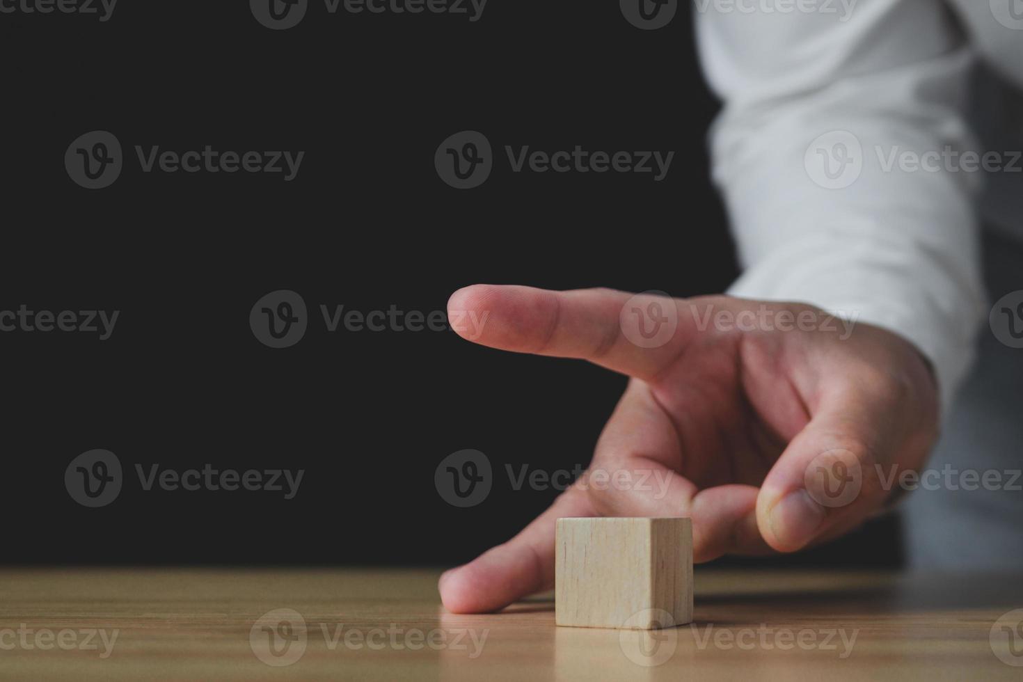 iemand gebruikt vingers om een houtblok te vegen. in het bedrijf toont het een verkoop of verlaging van een bedrijf om verlies te stoppen. strategie idee. dit close-up shot met een beetje focus. foto