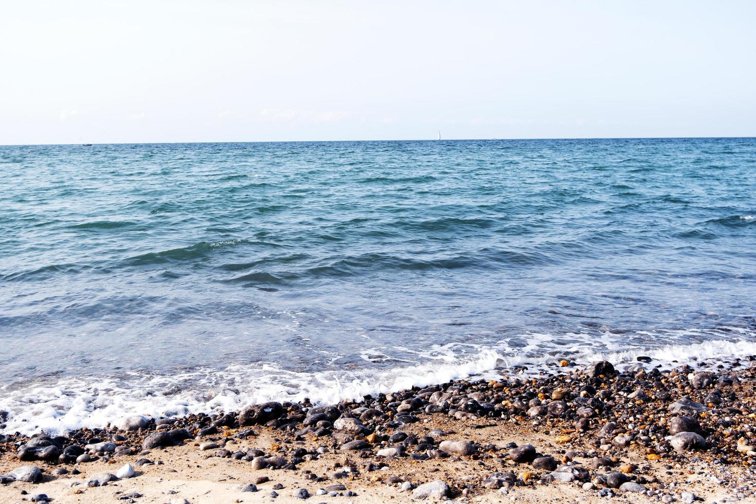 tedere oceaangolven en kiezelstenen aan de kustlijn, blauwe zeewateren op een zonnige dag, prachtige natuurlijke achtergrond van het zeegezicht foto