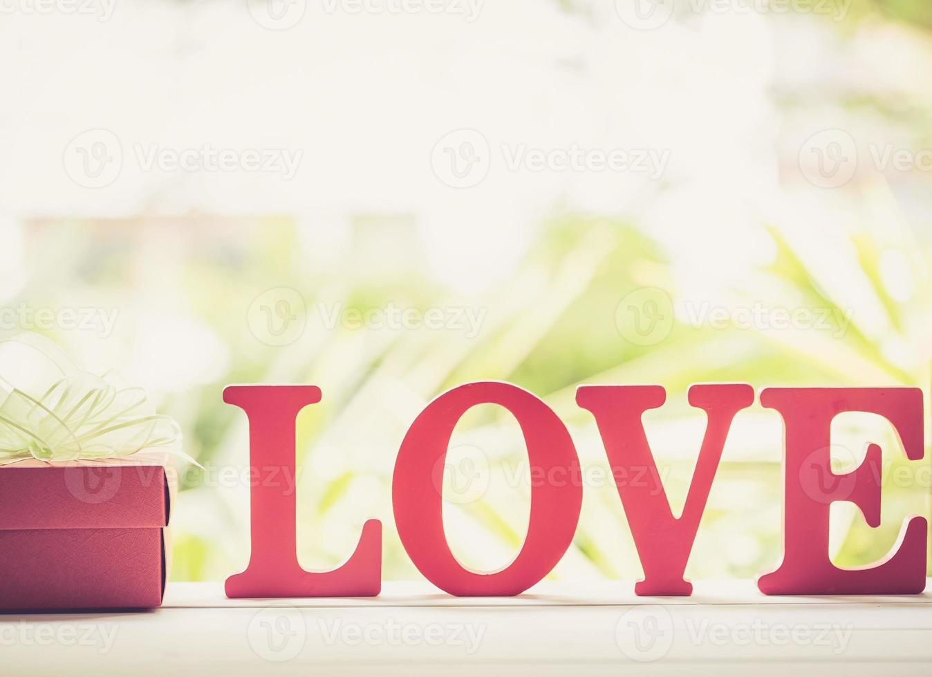 woord liefde houten tekst en geschenkdoos met striklint op houten tafel vintage retro toon, heden van romantische dag, teken en romantisch van valentijn, vakantieconcept. foto