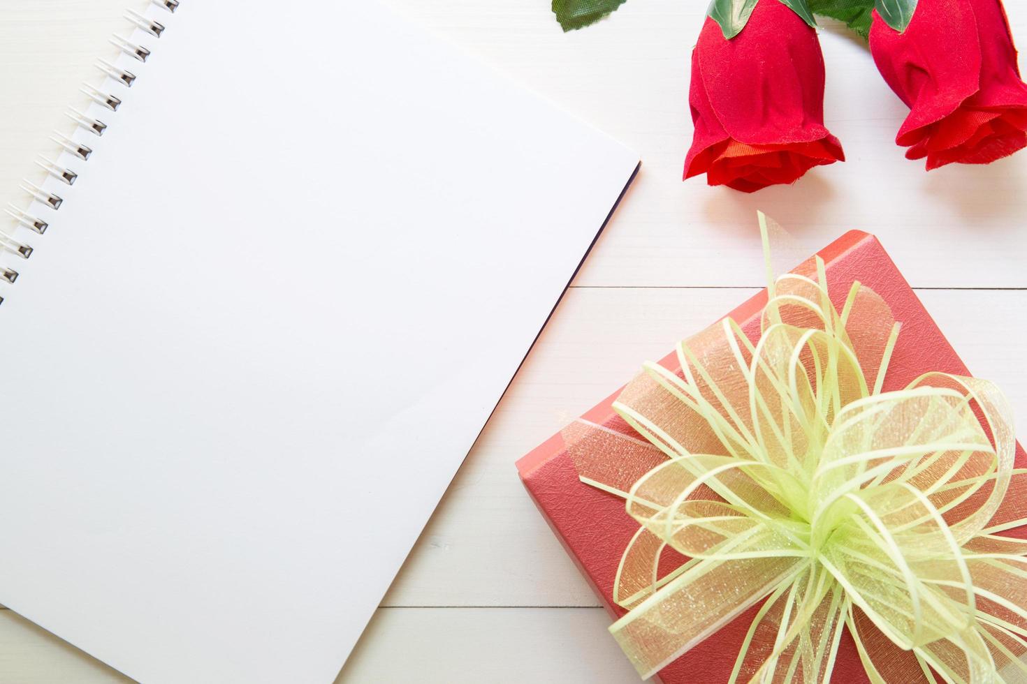 presenteren rode roos bloem en notebook en geschenkdoos met kopie ruimte op houten tafel, 14 februari van liefdesdag met romantisch, valentijn vakantieconcept. foto
