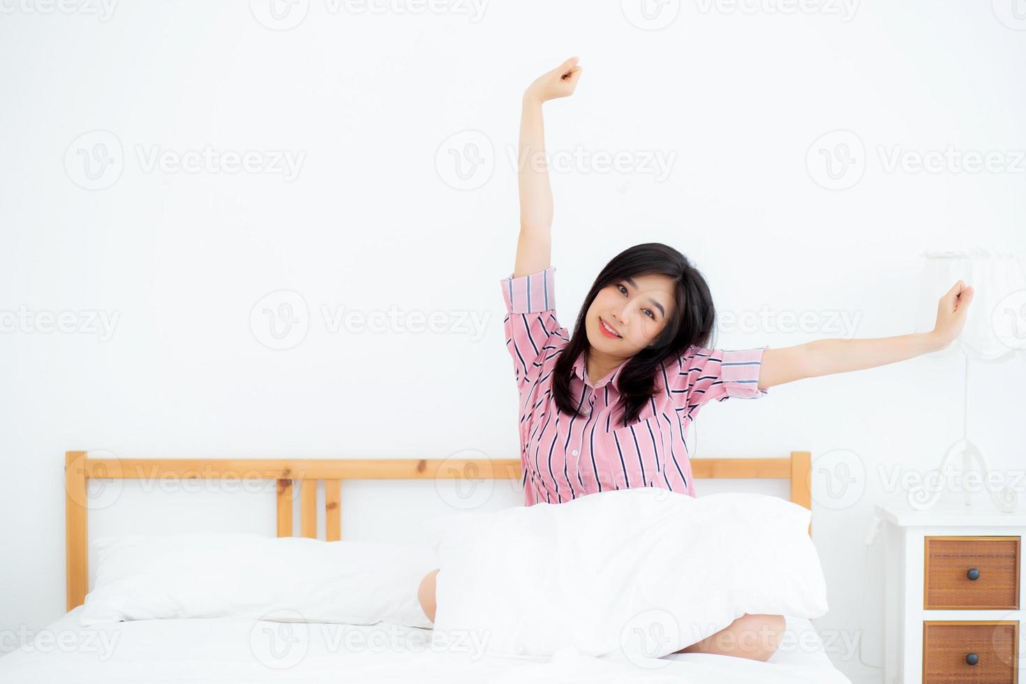 mooi van portret jonge aziatische vrouw strekken en ontspannen in bed na het wakker worden 's ochtends in de slaapkamer, nieuwe dag en rusten voor wellness, lifestyle concept. foto
