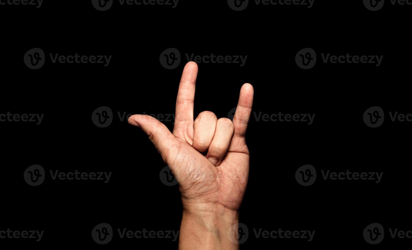 de hand van de man die zijn vinger vasthoudt, toont het symbool ik hou van je op een zwarte achtergrond. foto