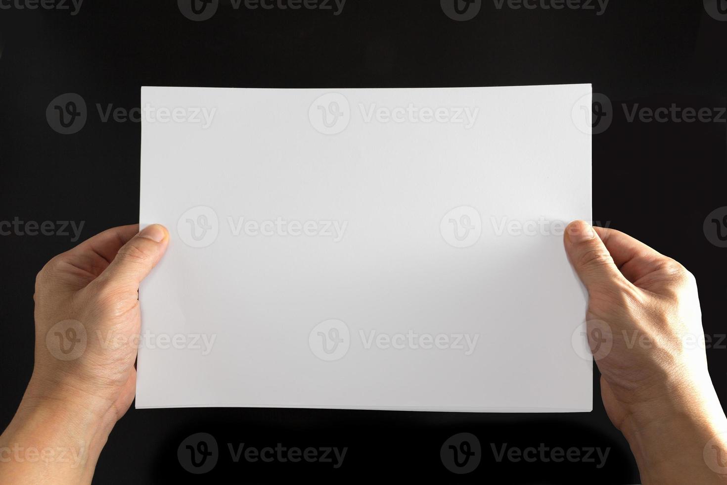 het concept van beide handen met een wit vel papier op een zwarte achtergrond. foto