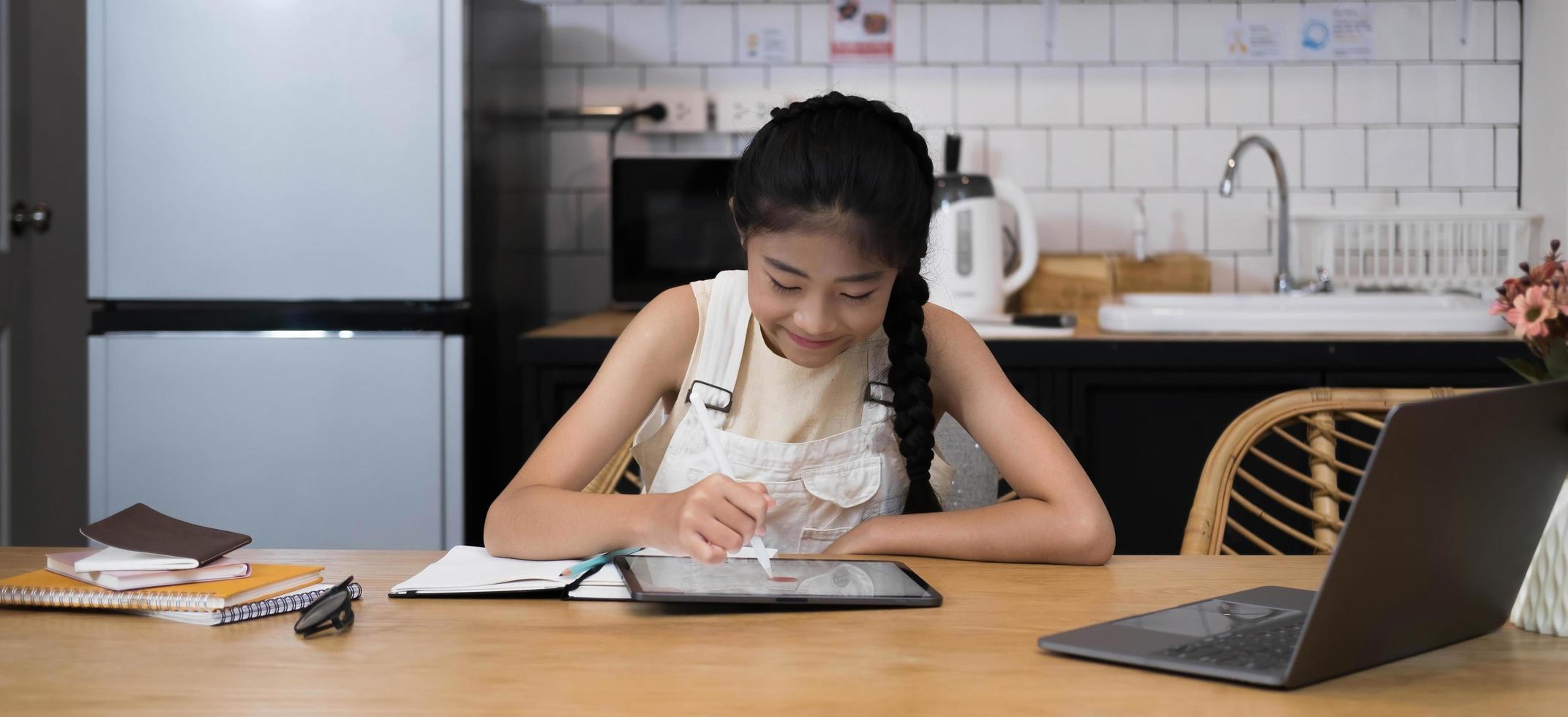 homeschool aziatisch klein meisje dat online les leert van schoolleraar door middel van een externe internetvergaderingstoepassing als gevolg van een pandemie van het coronavirus. kind op zoek naar computer laptop scherm die vrouw lesgeven. foto