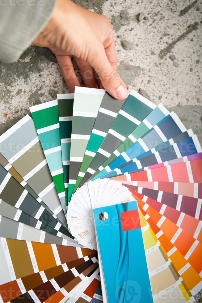 selectie van de verfkleur voor decoratieve huisreparaties aan het palet met lay-outs. een waaier van tinten in je hand in huis. reparatie en constructie, verf- en lakcoating foto
