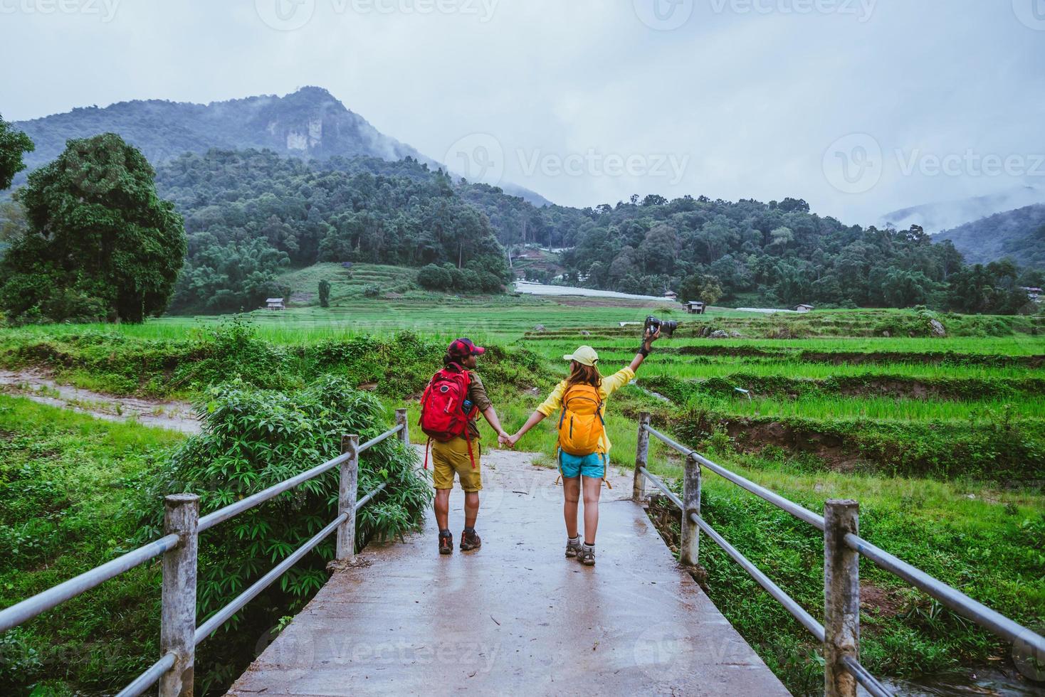minnaar aziatische man aziatische vrouwen reizen natuur. een foto lopen door het rijstveld en stoppen neem een pauze, ontspan op de brug bij ban mae klang luang in het regenseizoen.