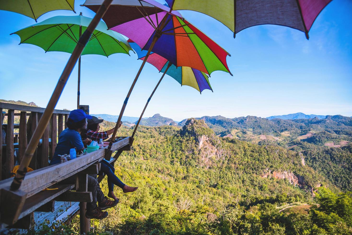 toeristen aziatisch paar zittend eten noedels op het houten platform en kijken schilderachtig uitzicht op prachtige natuur bergen bij verbod jabo, mae hong son, thialand. foto