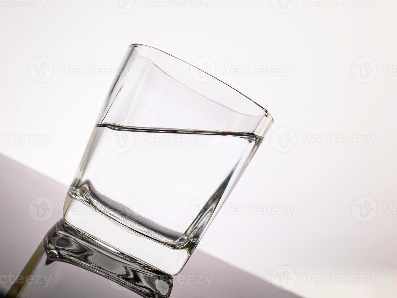 glas voor sterke drank doorschijnende elementen van glas worden op een gekantelde tafel geplaatst. lege objecten geïsoleerd op een witte achtergrond foto