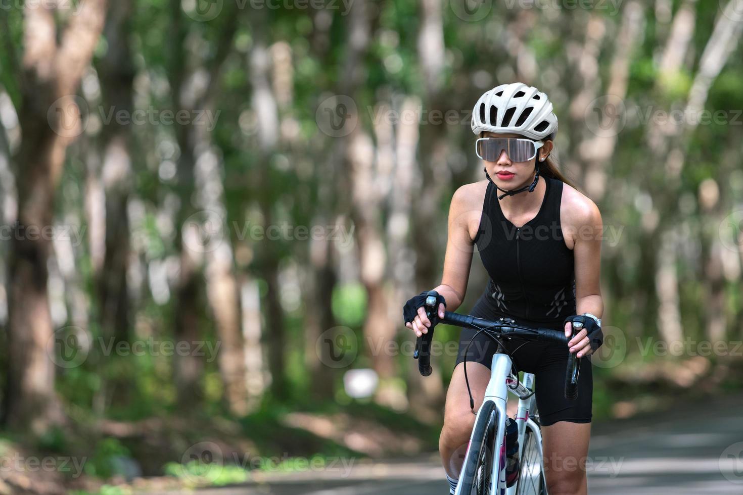 gelukkige vrouw fietsatleet bereidt zich voor op fietsen op straat, op de weg, met hoge snelheid voor oefenhobby en competitie in professionele tour foto