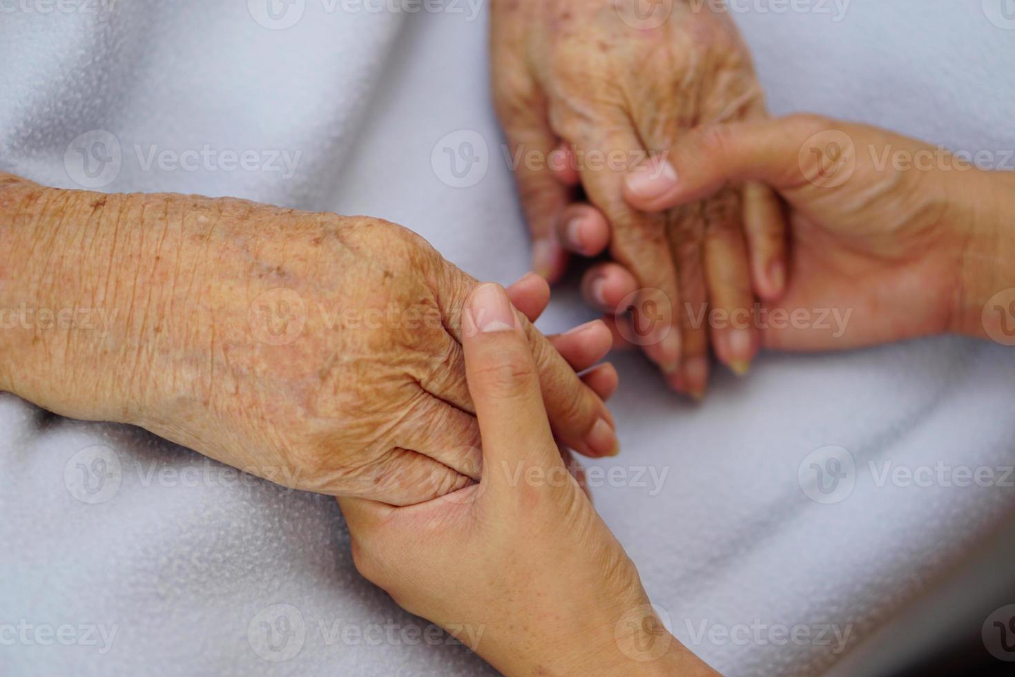 aanraken of hand in hand senior of oudere oude vrouw op een blauwe doek met liefde, zorg, aanmoediging en empathie. foto