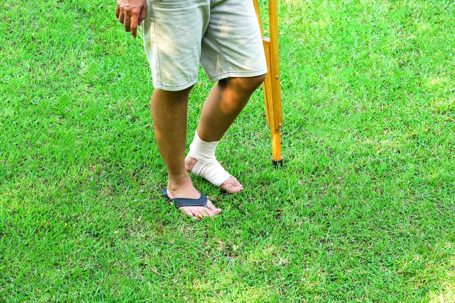 de afbeelding toont patiënten met enkelblessures met bandages enkelbrace en krukken gebruiken om het lopen op het gazon te ondersteunen. gezondheidszorg en medisch concept. foto