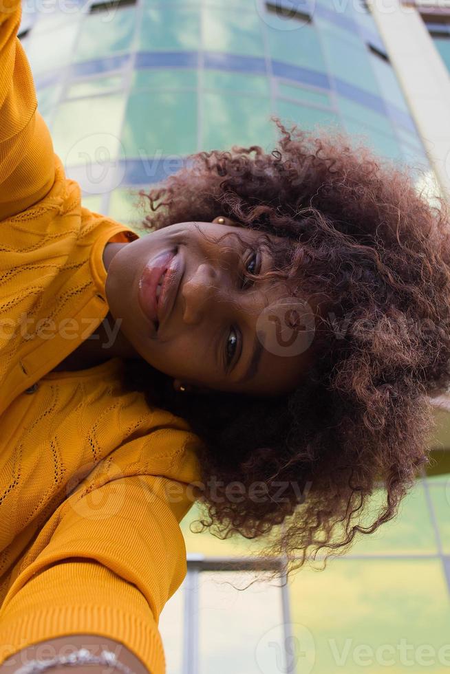 een gelukkige en jonge Afro-Amerikaanse vrouw neemt een selfie, close-up foto
