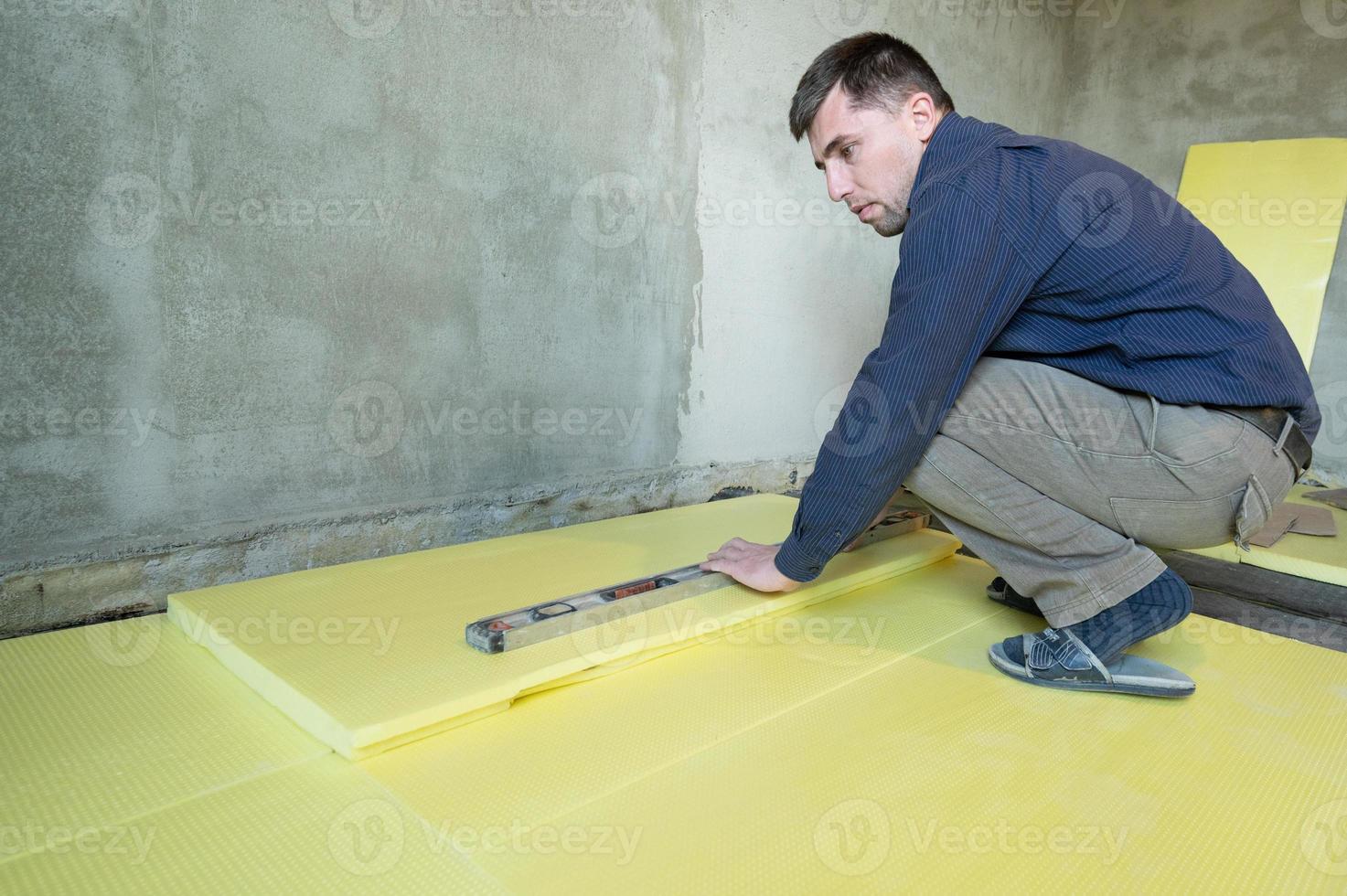 installatie van geëxpandeerd polystyreen in de kamer voor vloerisolatie, reparatiewerkzaamheden alleen, geel geëxpandeerd polystyreen. foto