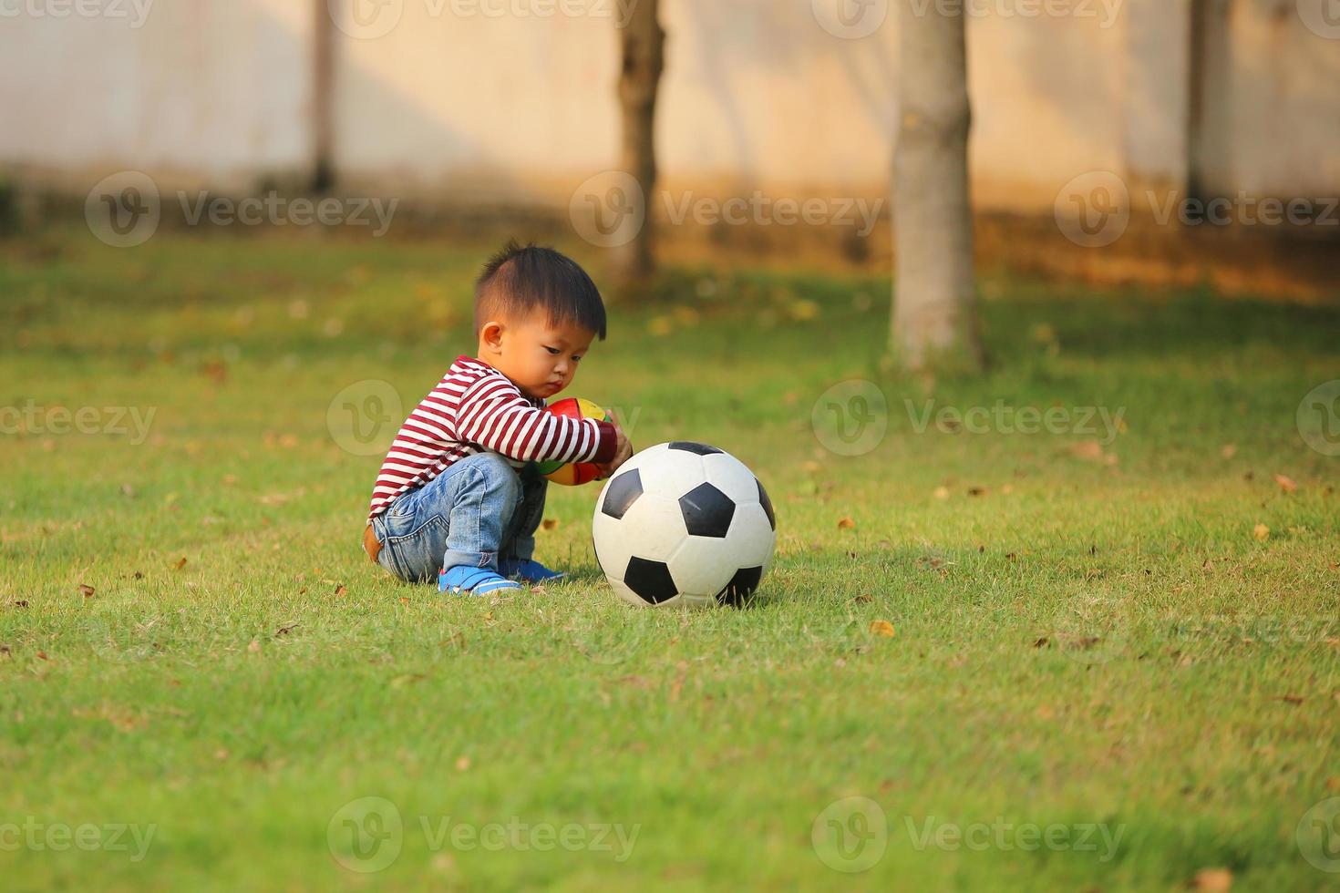 Aziatische jongen voetballen in het park. jongen met ballen in grasveld. foto