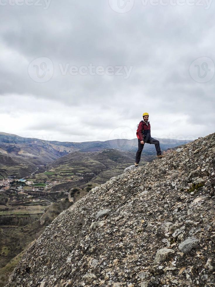 jonge man in gele klimhelm die naar het berglandschap kijkt foto