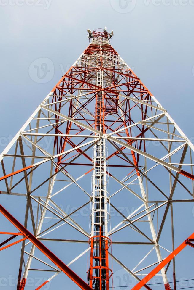 telecommunicatiemast met microgolfverbinding en tv-zenderantennes over een blauwe hemel. foto
