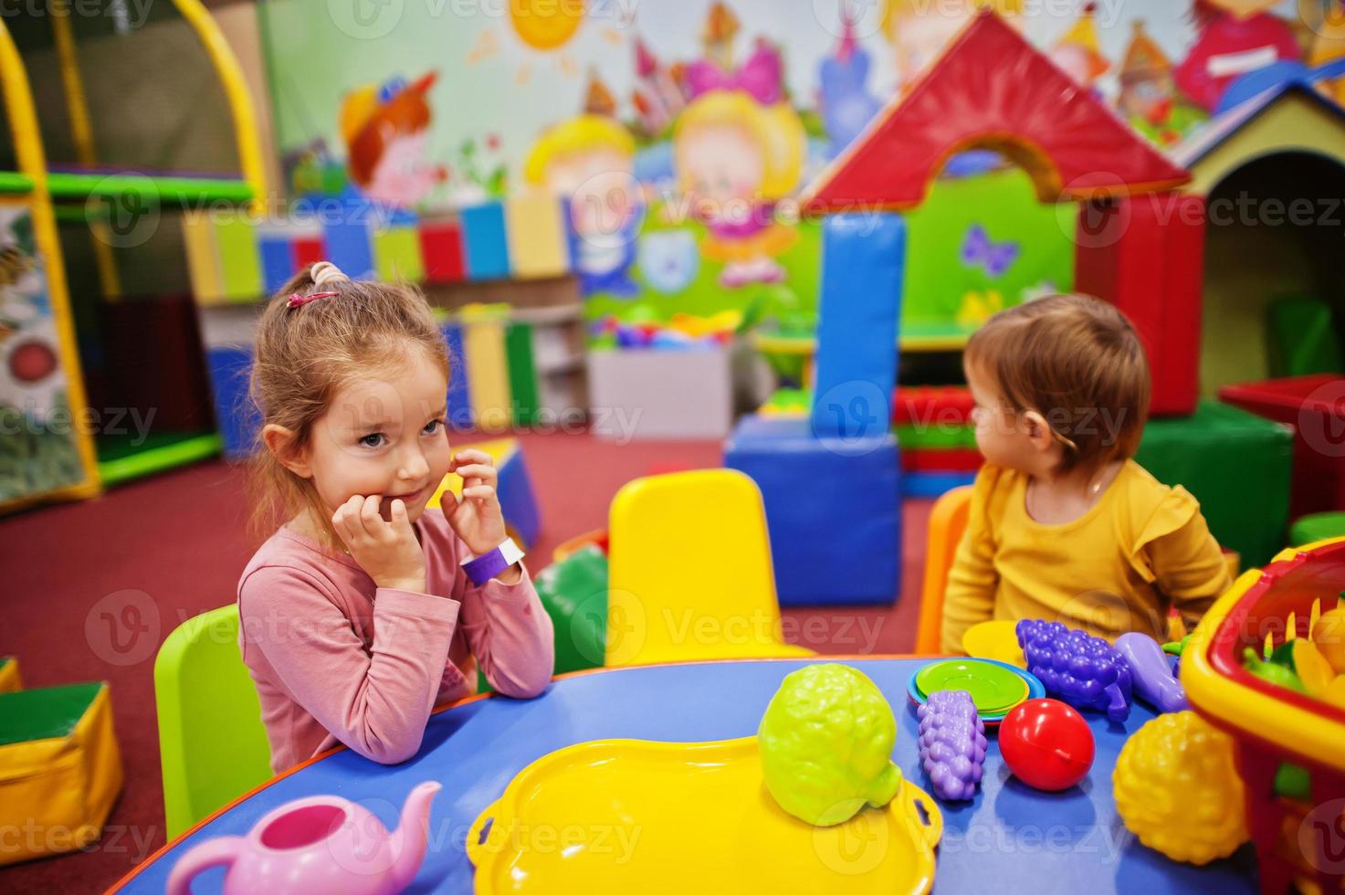 schattige zusjes spelen in indoor speelcentrum. kleuterschool of voorschoolse speelkamer. in de kinderkeuken. foto