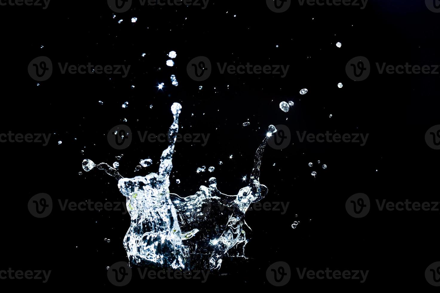 verspreide waterspatten op een zwarte achtergrond. waterplons geïsoleerd op de zwarte achtergrond foto