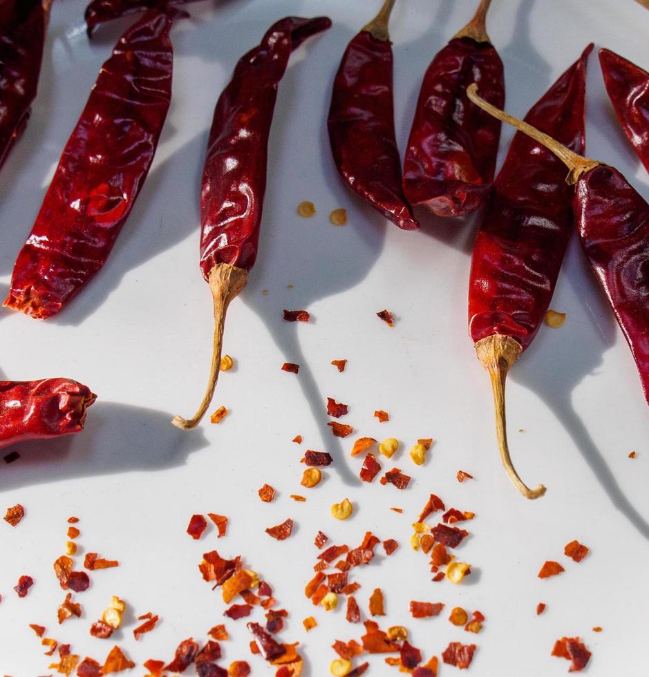 rode chili pepers, chili peper vlokken getoond tegen een witte achtergrond foto