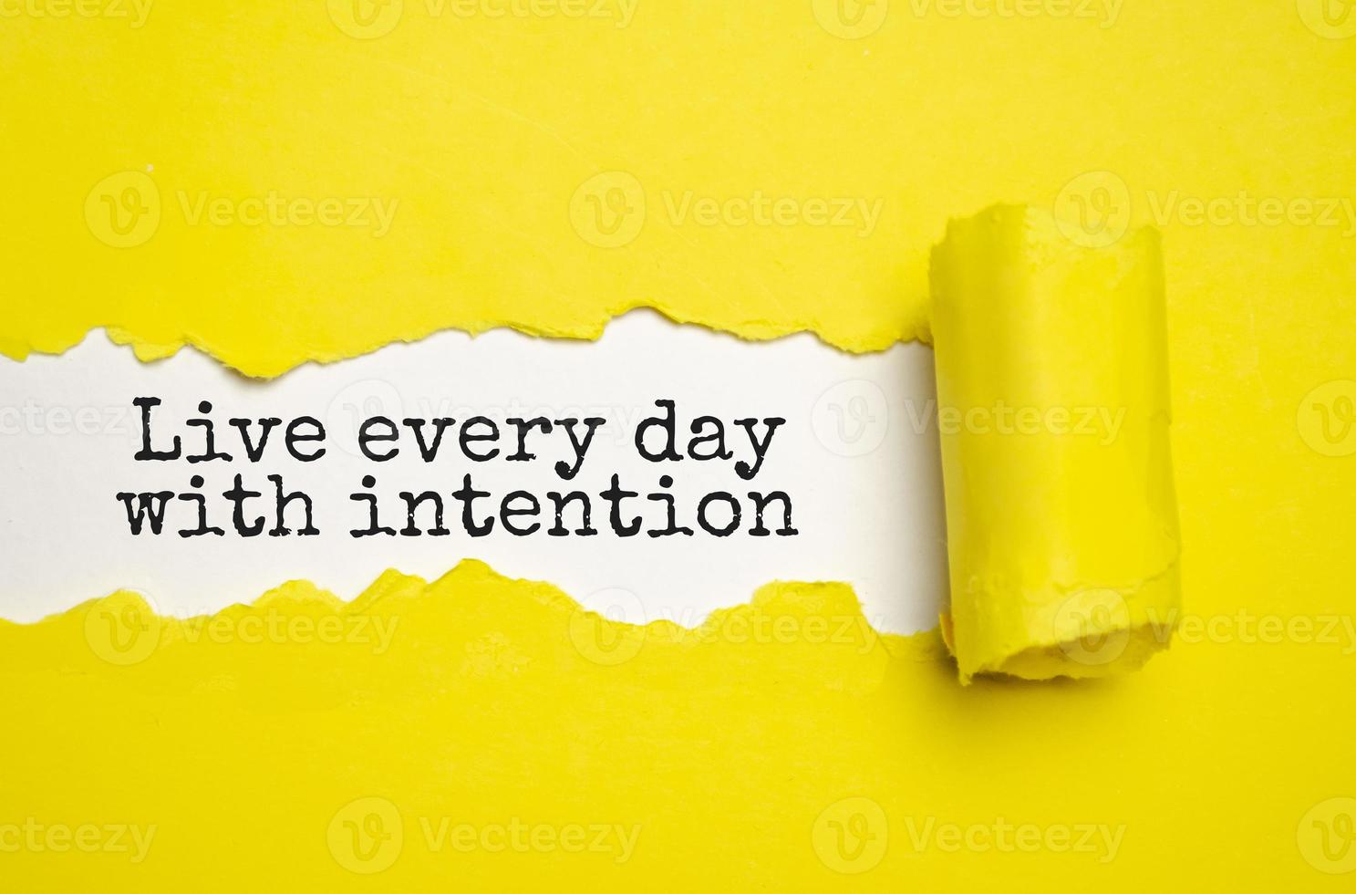 leef elke dag met intentie. woorden geschreven onder gescheurd papier. motivatie concept tekst. foto