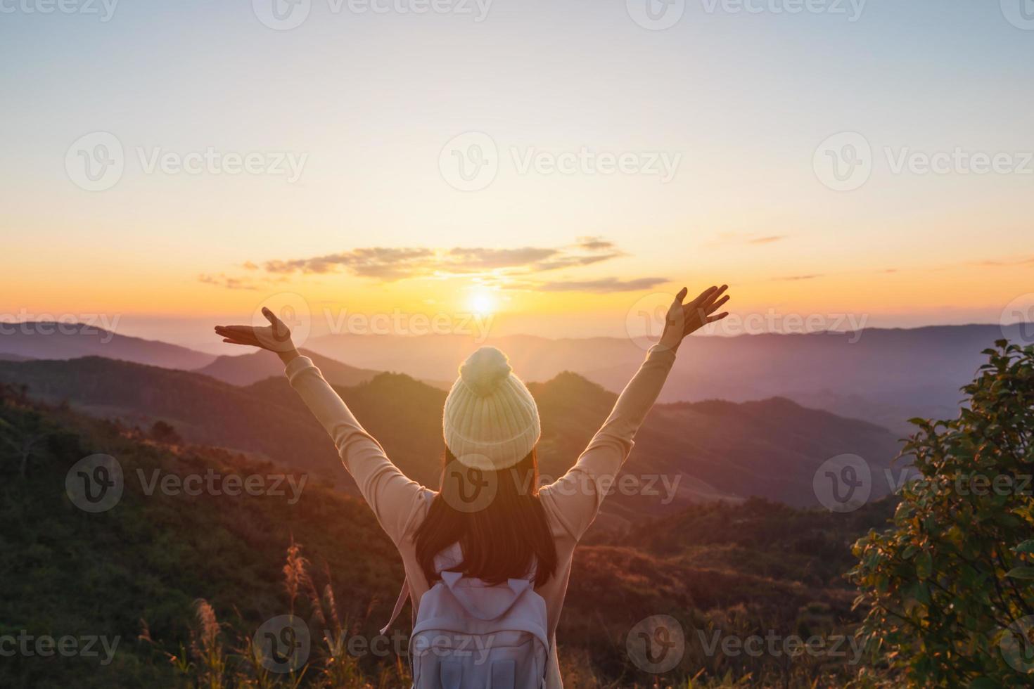gelukkige jonge vrouw reiziger ontspannen en kijken naar de prachtige zonsondergang op de top van de berg foto