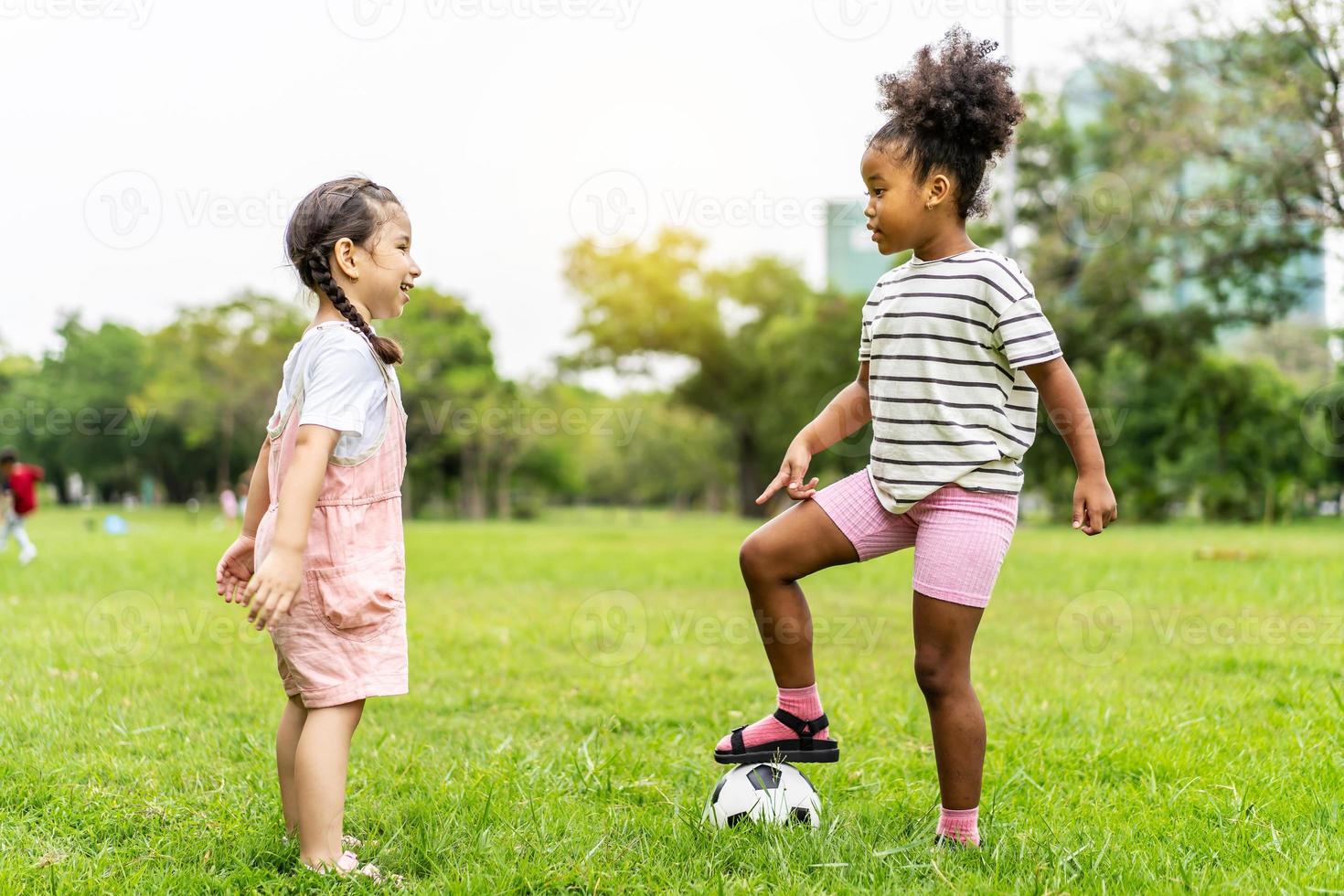 twee schattige kleine Afro-Amerikaanse voetballen samen op het gras op een zonnige zomerdag, oefening voor de gezondheid. sport- en kinderconcept. foto