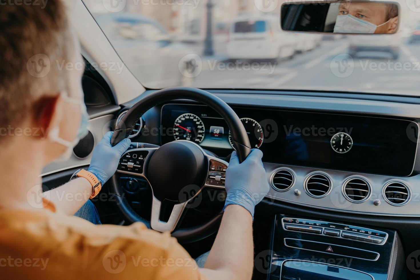 schot van man bestuurder draagt beschermend medisch masker en rubberen handschoenen, poseert in auto, geeft om gezondheid tijdens coronavirus. veiligheid in het vervoer. gezondheidszorg foto