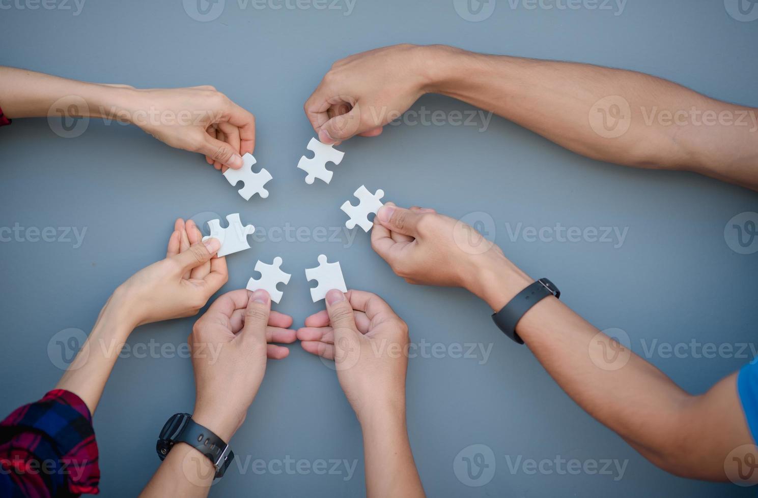 een beeld op hoog niveau van zakenmensen die puzzels oplossen op een grijze achtergrond foto