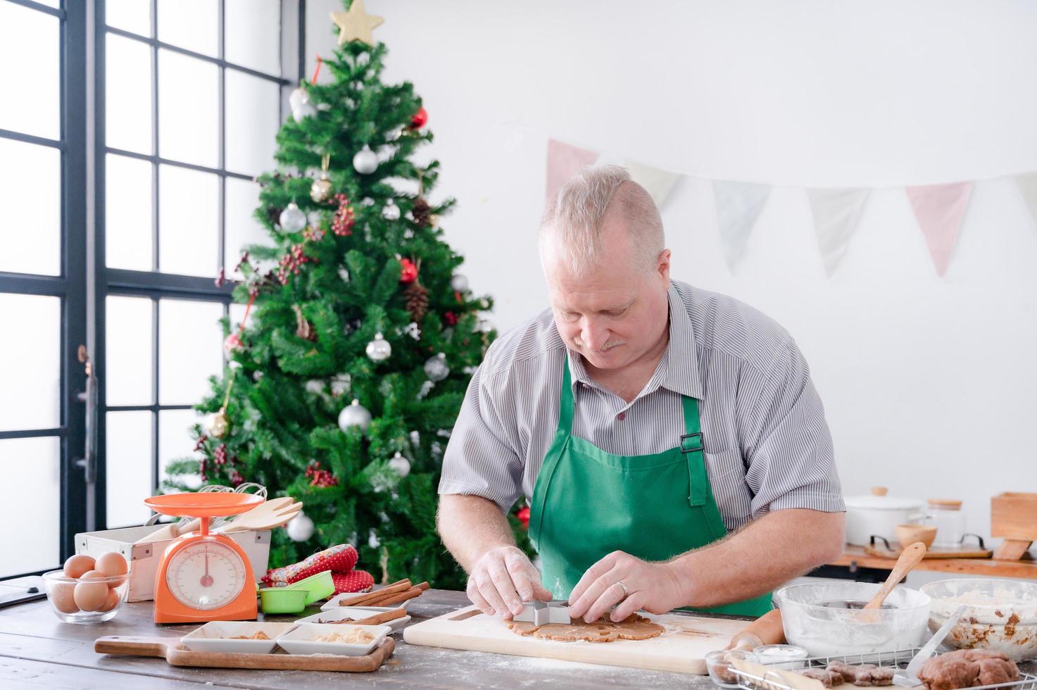 een europese vader drukt de vorm op het deeg en bereidt de peperkoekbakingrediënten die hij en zijn gezin maken voor kerstmis en nieuwjaar foto