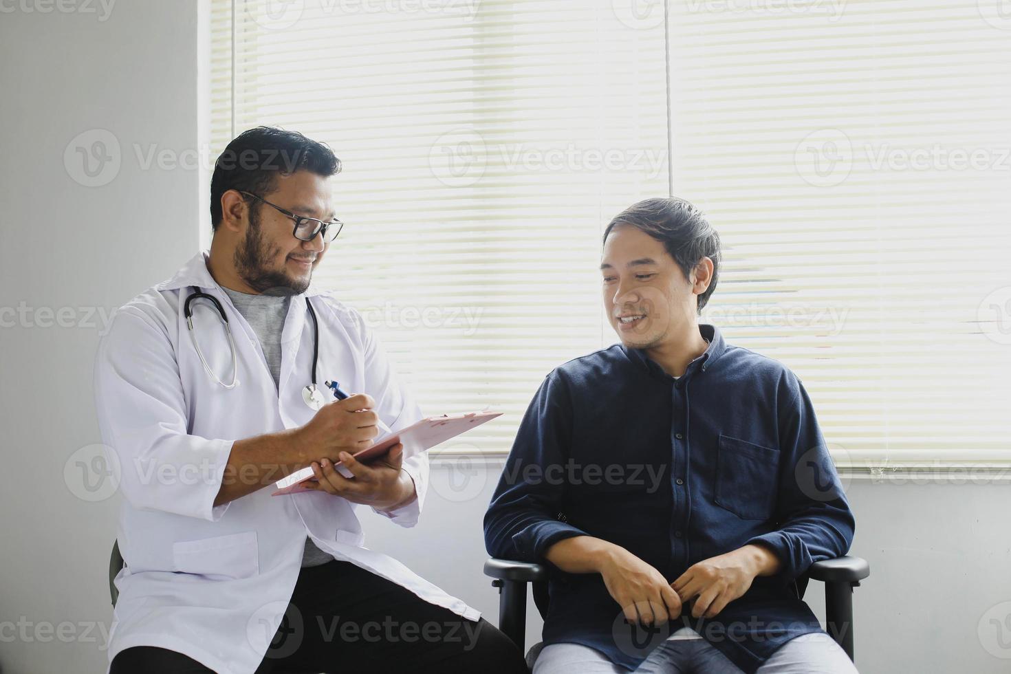 vrolijke arts en patiënt tijdens het nemen van het medisch dossier van de patiënt foto