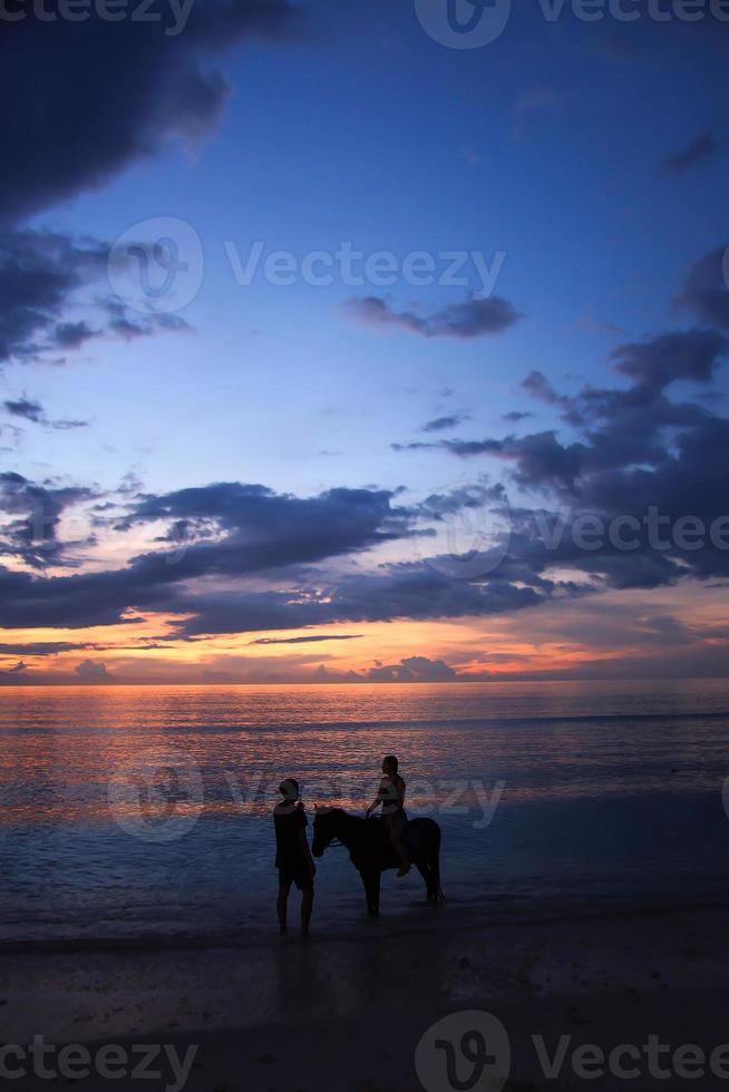 paardrijden bij de zonsondergang onder dramatische violette lucht foto