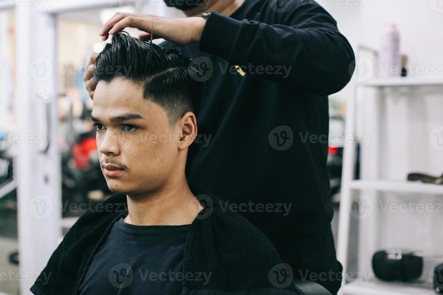 jonge man bij kapperszaak. kapper maakt het haar van de consument recht. zelfzorg, mannelijke schoonheid. kapper. moderne haarstijl foto