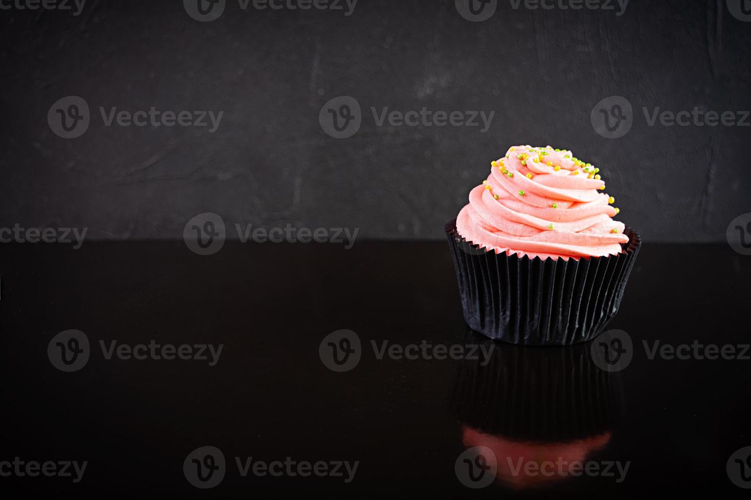 smakelijke kleurrijke cupcakes geïsoleerd op een donkere achtergrond. heerlijke cupcake foto