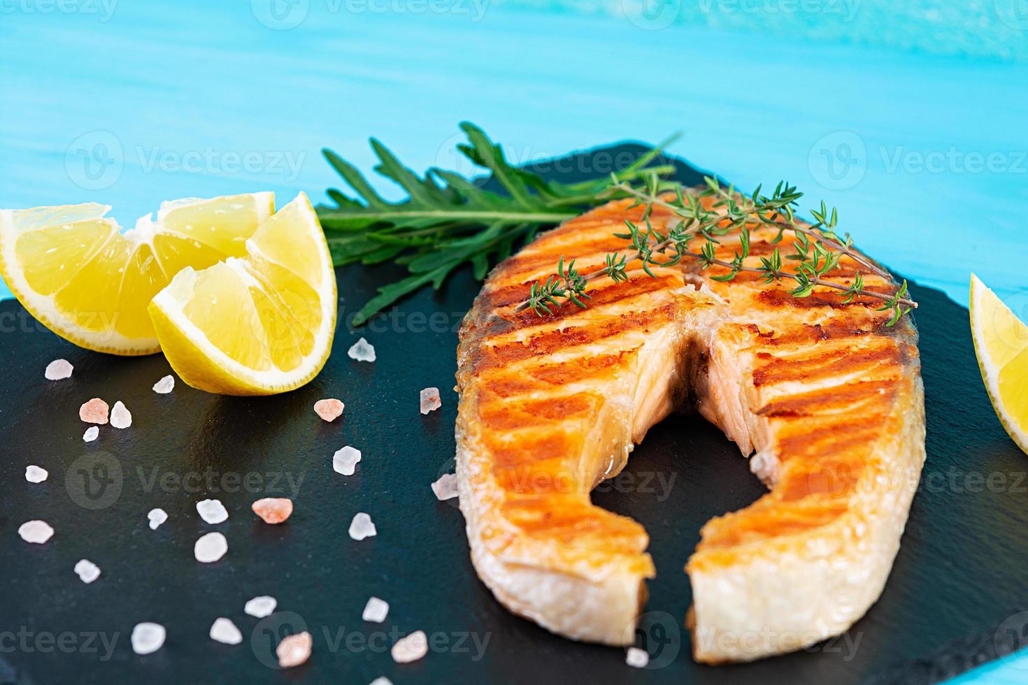 gegrilde zalm vis op stenen bord. Salt atlantic zalm gebakken op grill met citroen foto