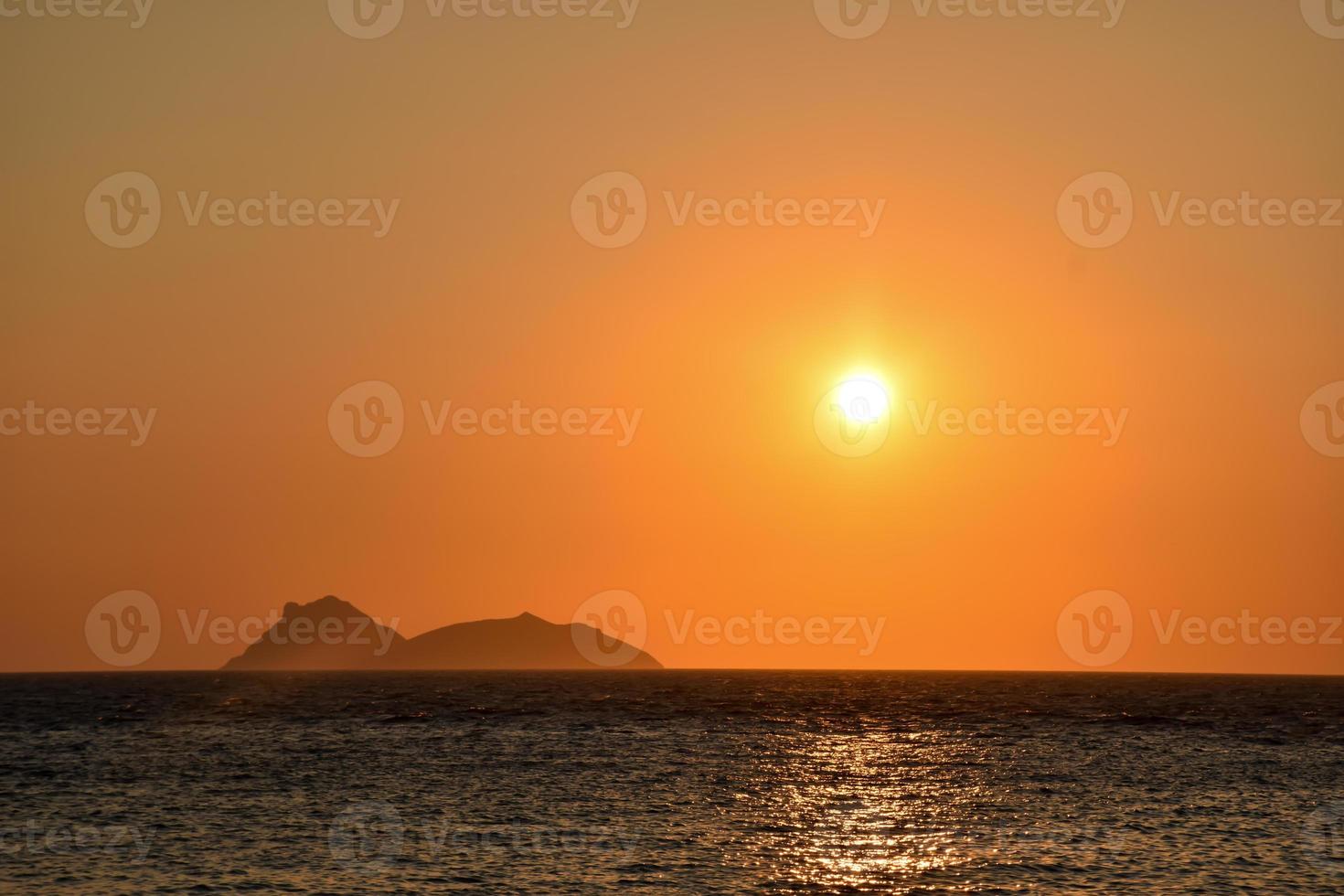 oranje zonsondergang op het hippiestrand van Matala met uitzicht op de Paximadia-eilanden op Kreta, Griekenland foto