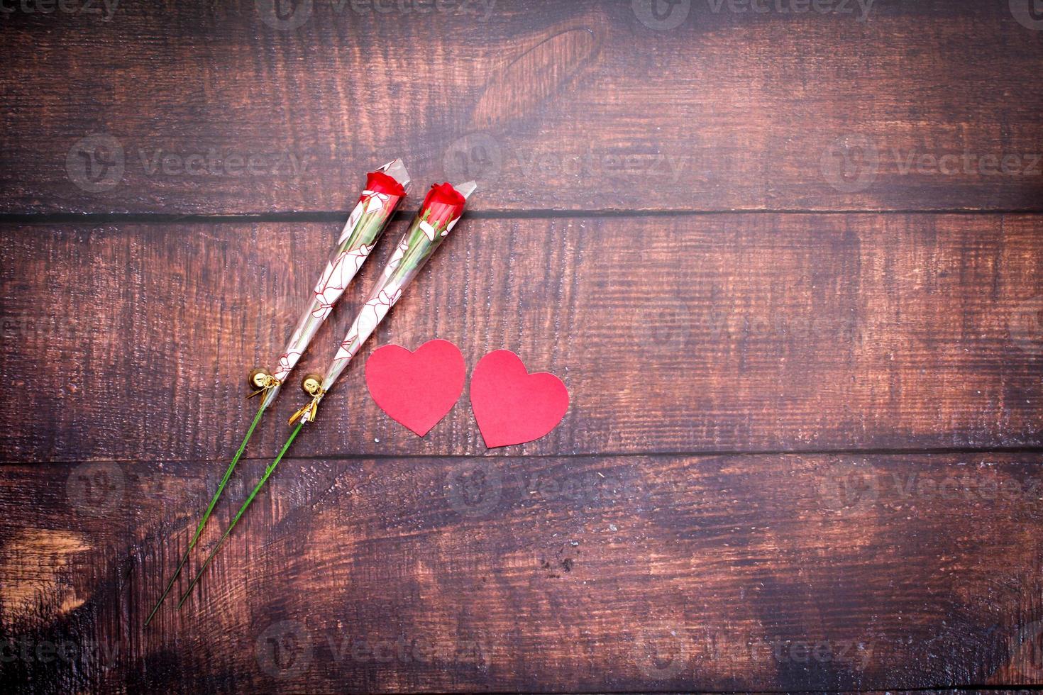 papieren hartjes en rode rozen op houten vloeren foto