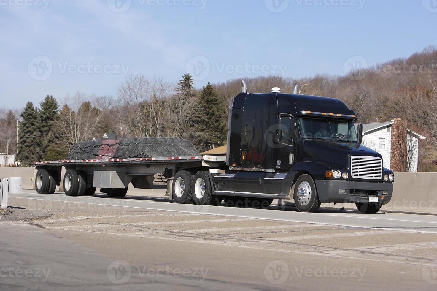 geladen flatbed zwarte semi vrachtwagen foto