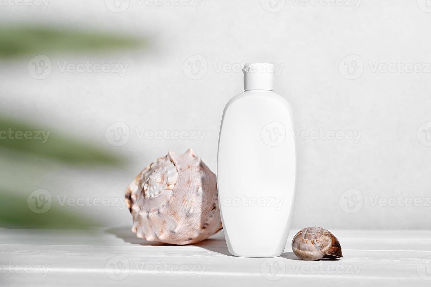 witte fles cosmetische zonnebrandcrème of vochtinbrengende crème voor het lichaam naast schelpen. mockup-sjabloon voor zomerhuidbescherming met uv-scherm foto