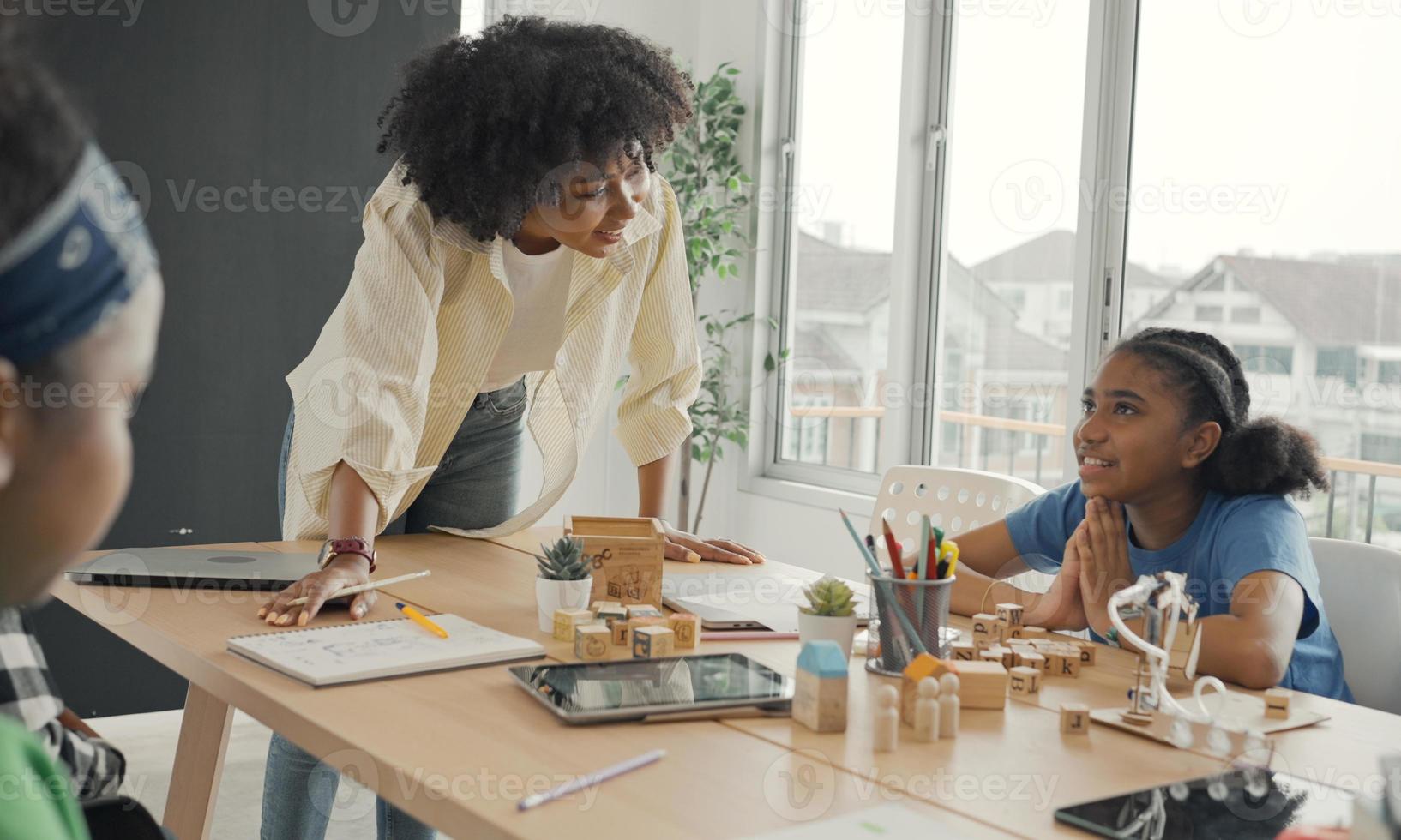 klaslokaal met diverse leerlingen van gelukkig Afro-Amerikaanse studenten en leraar die samen activiteiten doen. de leraar geeft les, begeleidt en praat met de kinderen in divers. foto