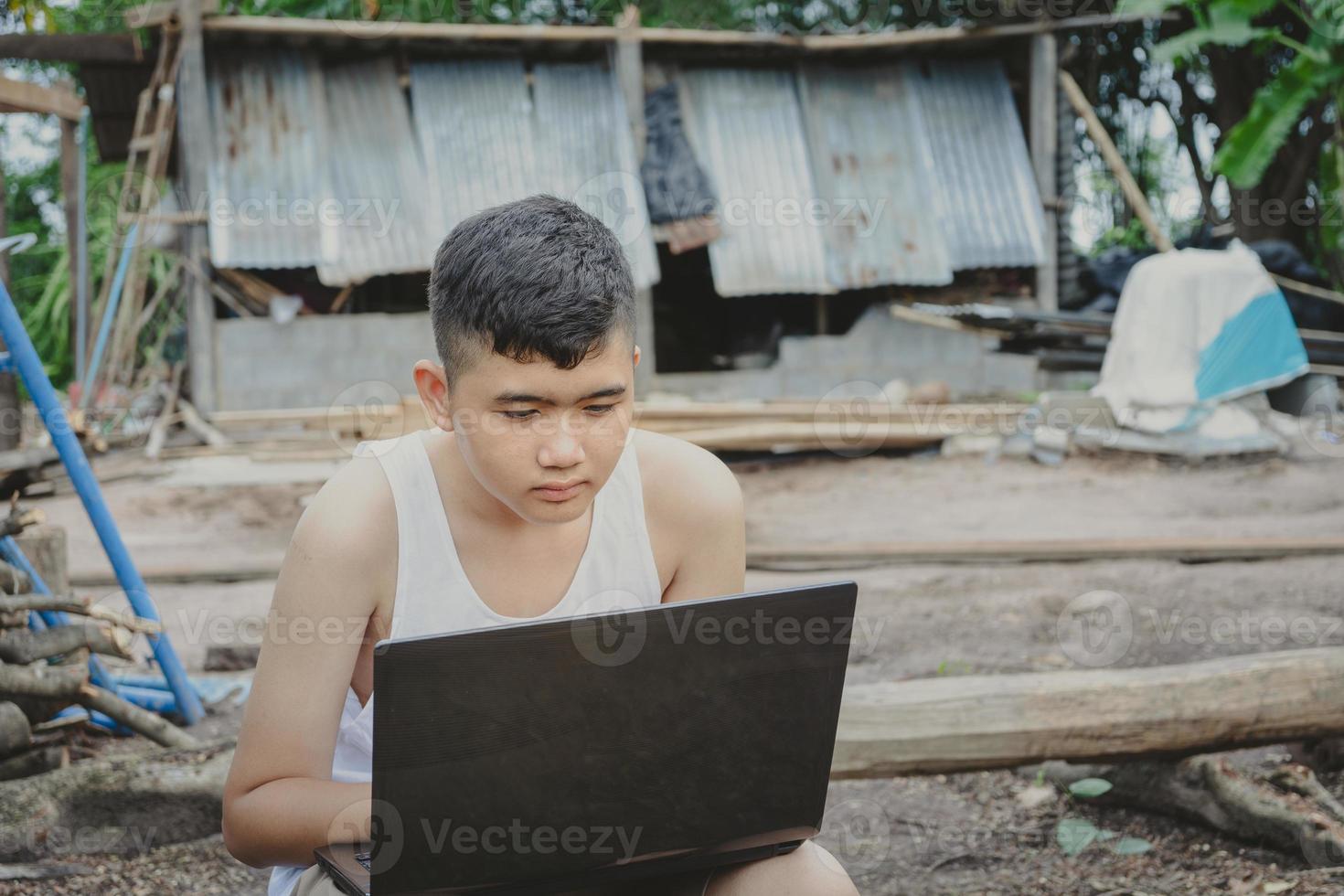 Aziatische jongen studeert online met laptop op zijn bureau thuis platteland, leren met leraar thuis, thuisonderwijs afstand leren online internet landelijk, slecht gebrek aan educatieve apparatuur foto