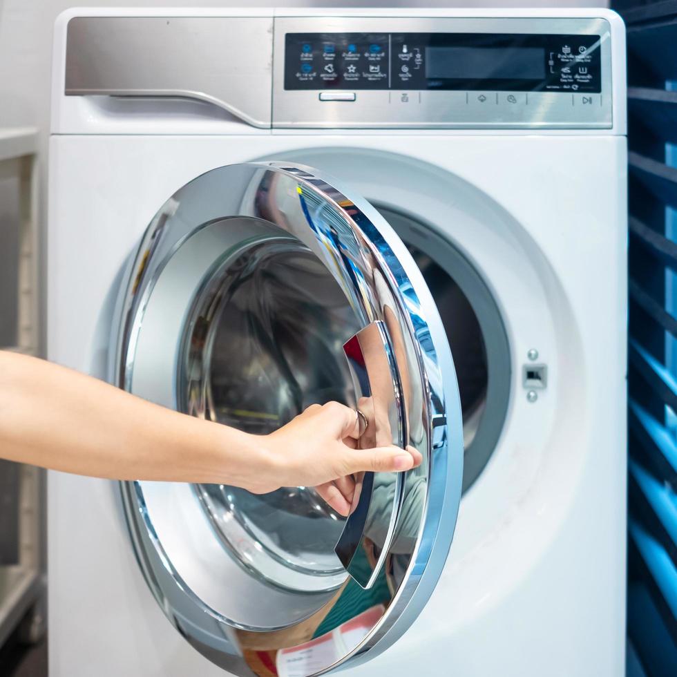 huisvrouw vrouw hand met kleren in wasmachine in wasruimte foto