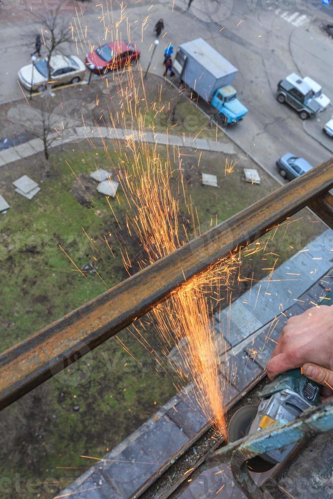 een arbeider snijdt metaal met een molen. foto