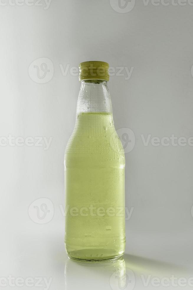 glazen fles met geel water op witte achtergrond foto