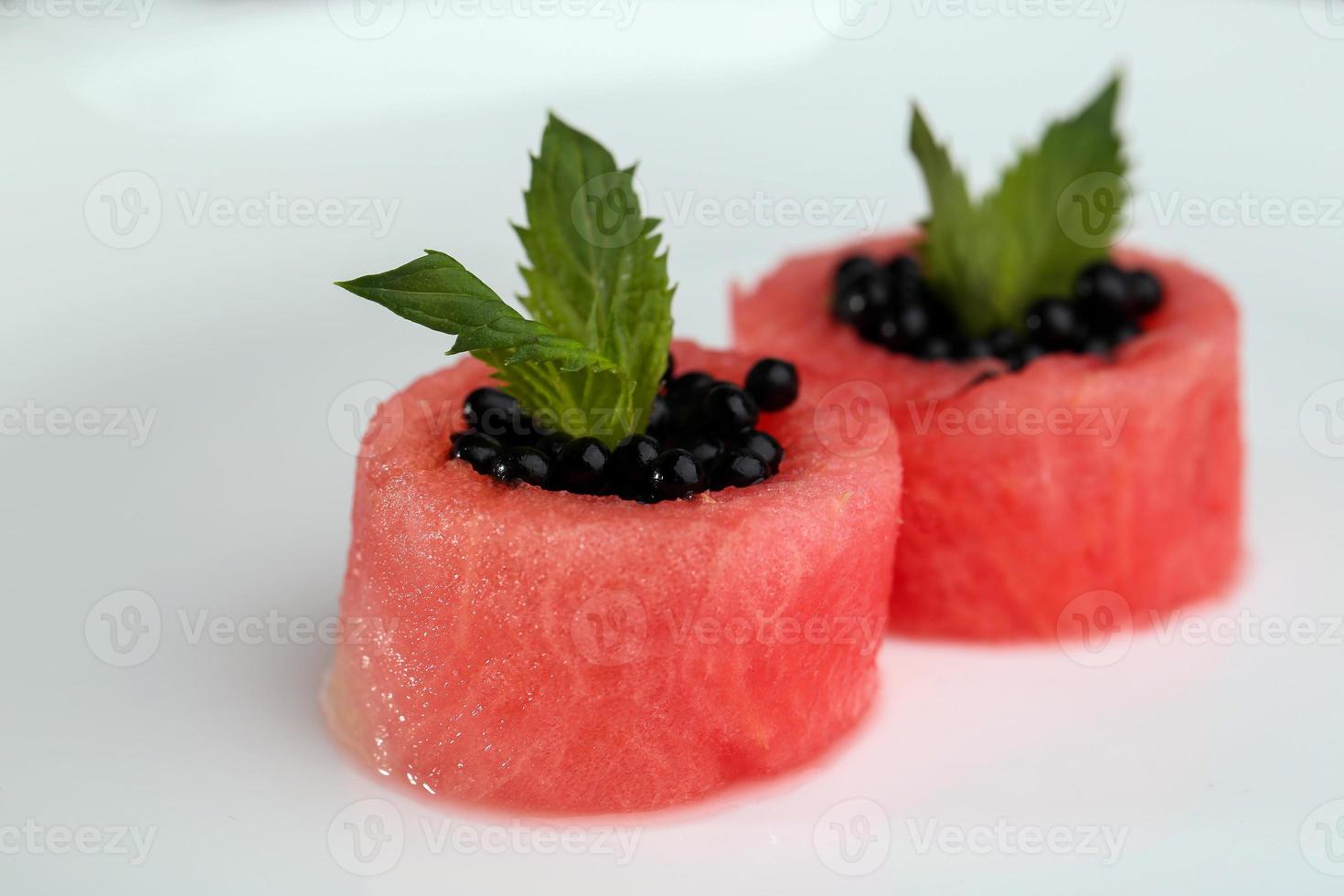 schotel van watermeloen met zwarte kaviaar op een witte plaat foto