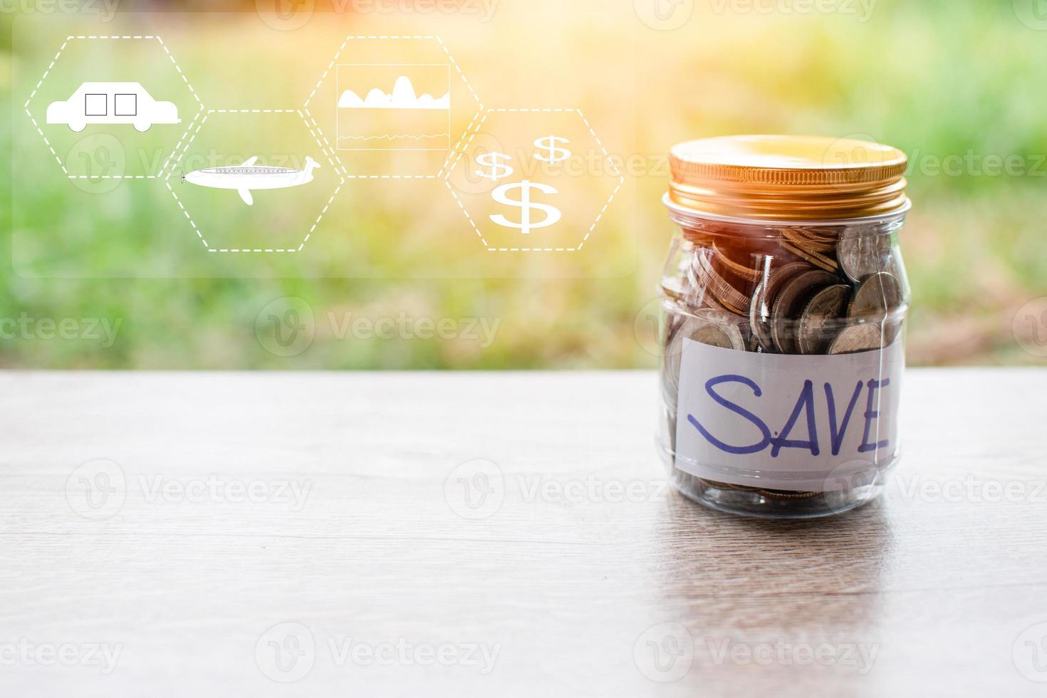 munten en tekst worden opgeslagen in een glazen pot op een houten tafel. concept van geld besparen voor investeringen en noodsituaties. close-up, onscherpe achtergrond foto
