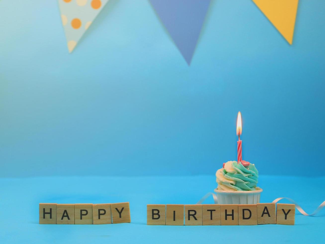 zoete cupcake en boog kaars op blauwe achtergrond met kopie ruimte. gelukkig verjaardagsfeestje foto