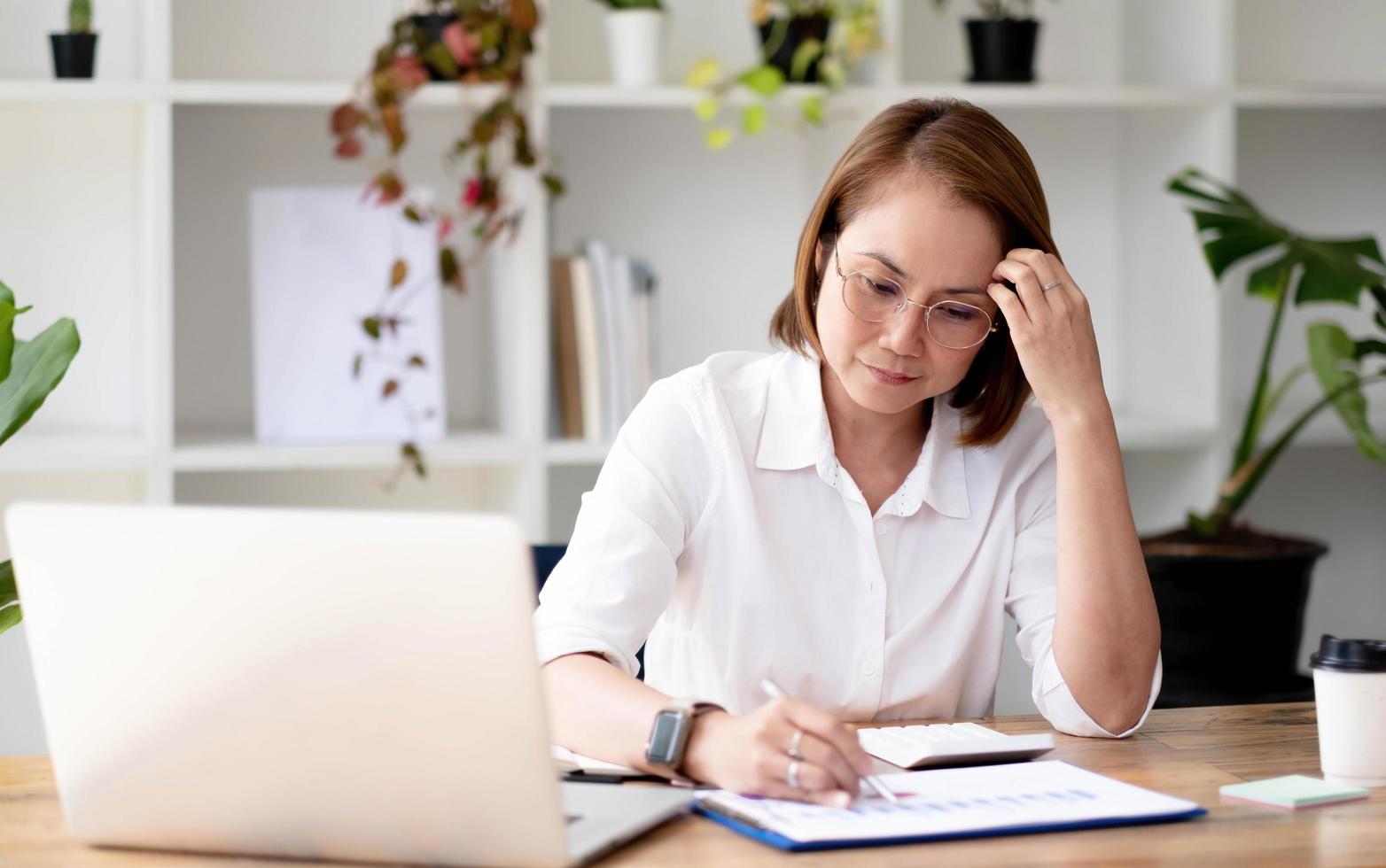 Aziatische senior-vrouw van de hogeschool met een bril die het rapport van haar student in haar moderne huis bekijkt en onderzoekt. foto