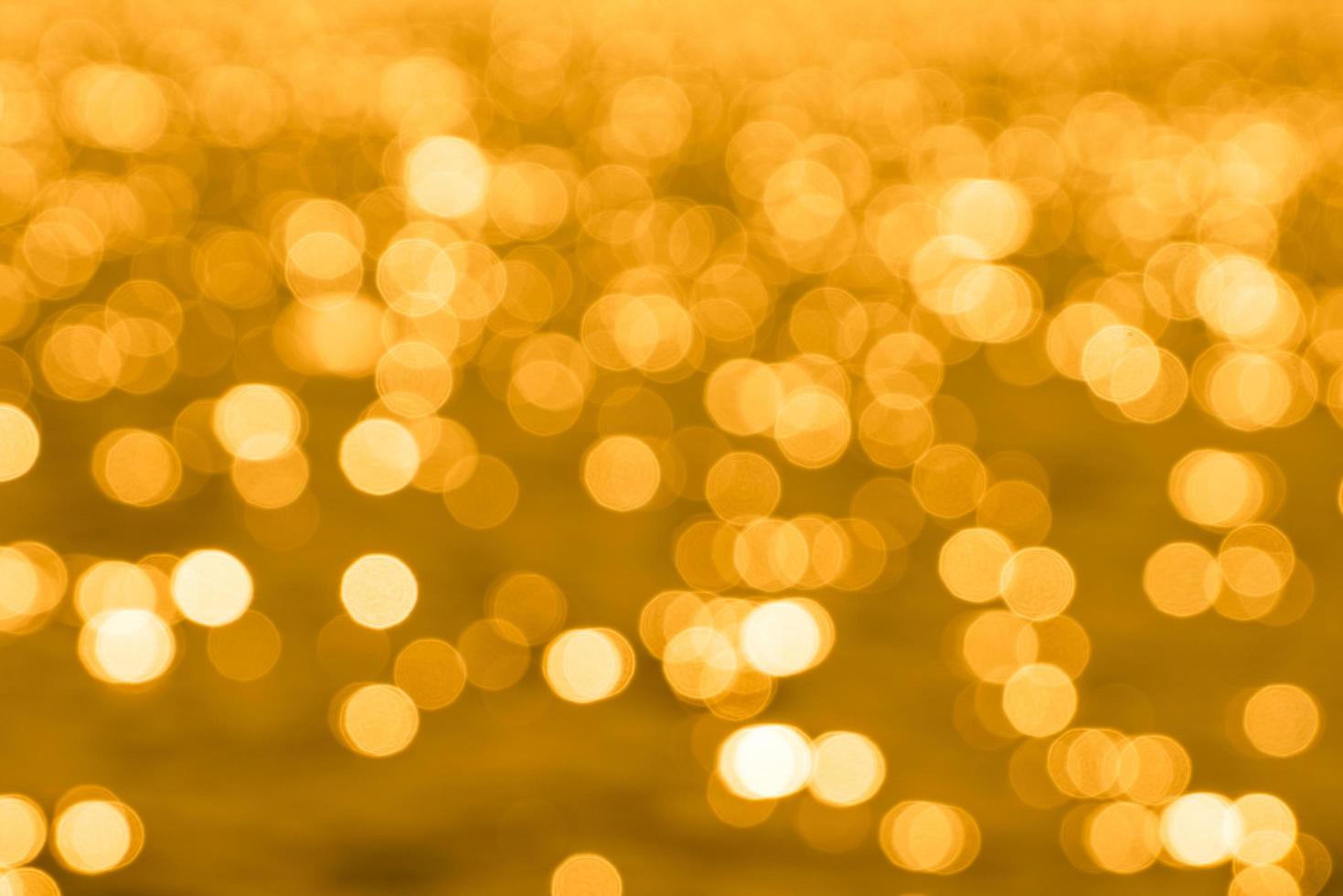 bokeh licht van reflectie van gouden wateroppervlak in de avond zonsondergang foto