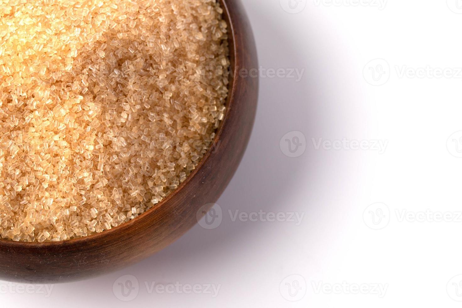 bruine suiker in een houten kopje op een witte achtergrond foto